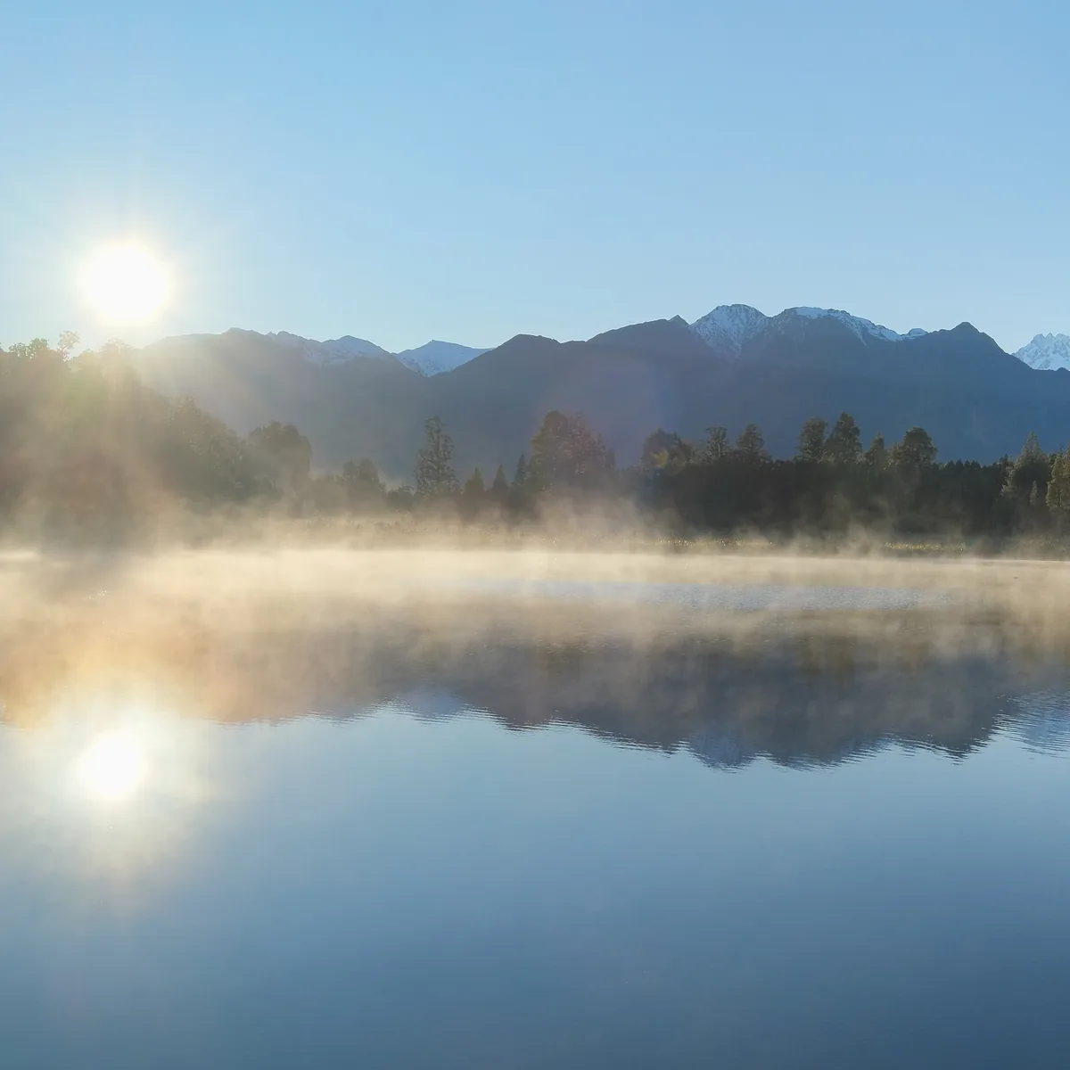 Soft morning light and mist over a calm mountain lake